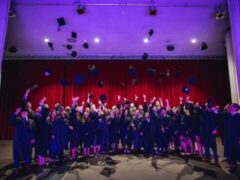 A gorup of people throw their hats in the air at the graduation ceremony