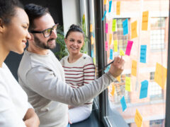 A meeting between three people at a window with post-its