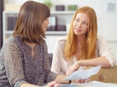Two women talking. The first one has orange hair the other one has brown hair