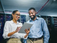 A woman and a man look at a tablet and laugh.